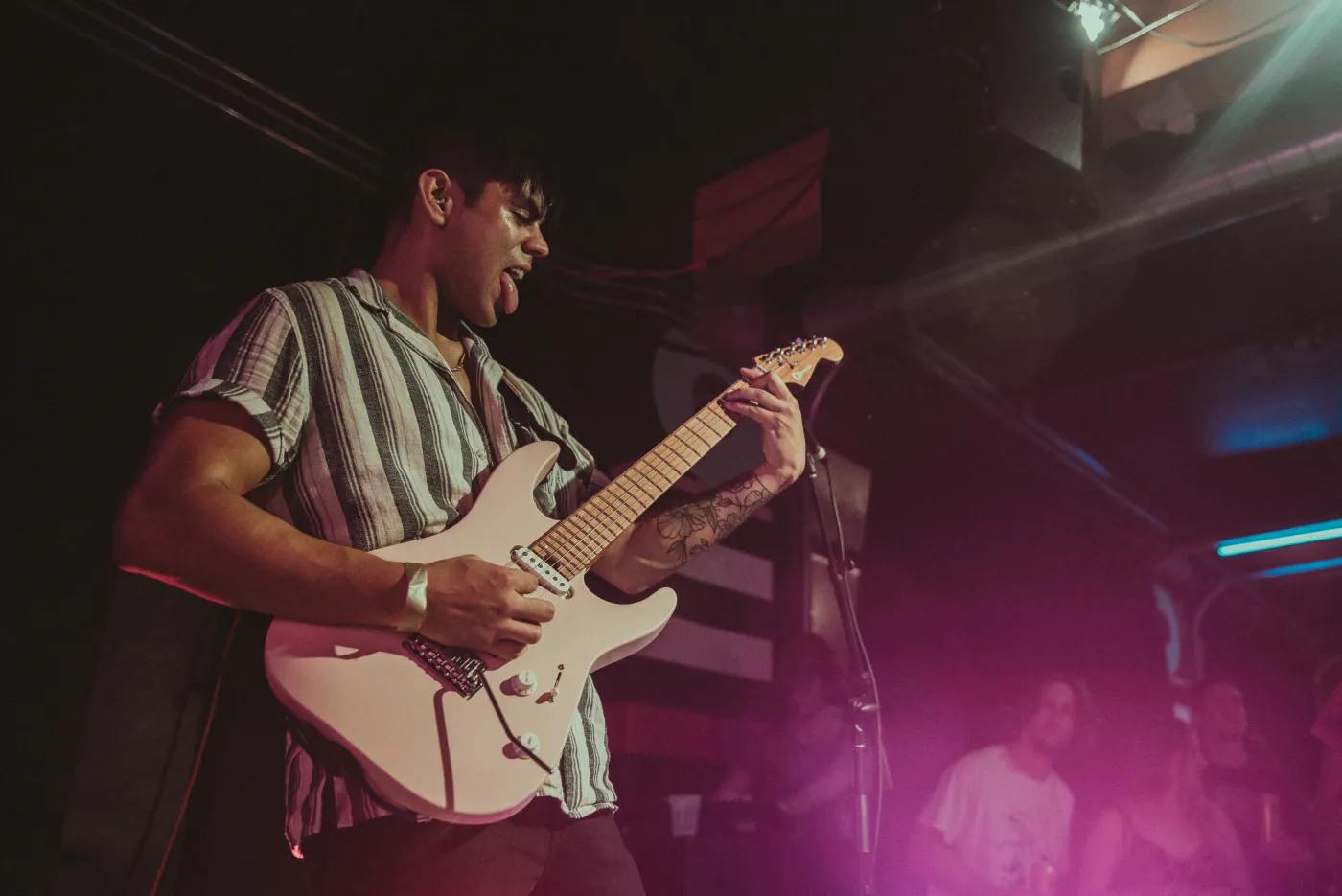 Luke playing guitar under pink stage light