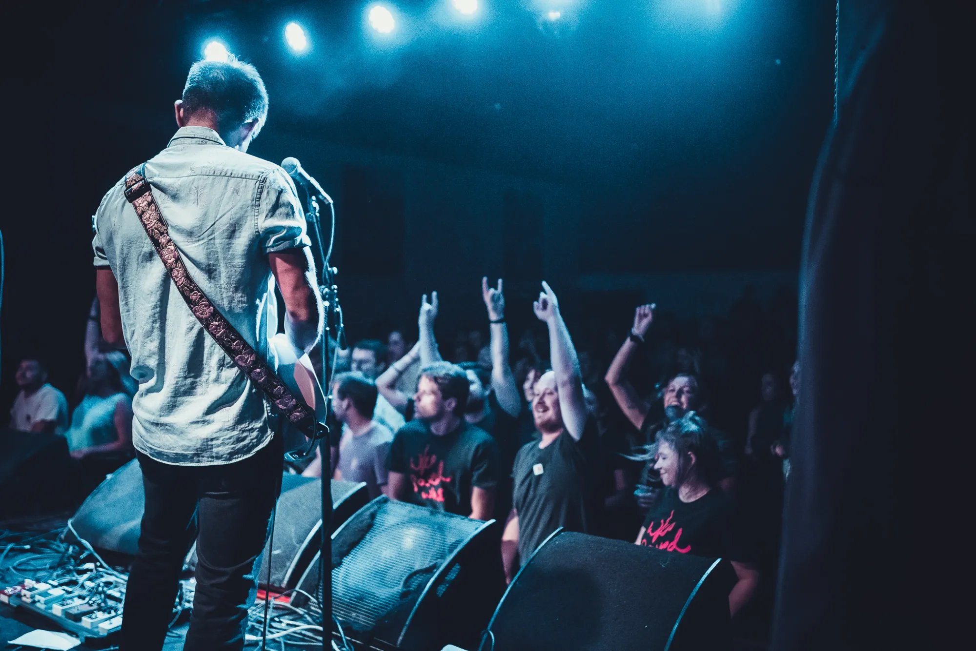 Who Saved Who on stage, seen from behind, facing a crowd throwing up horns